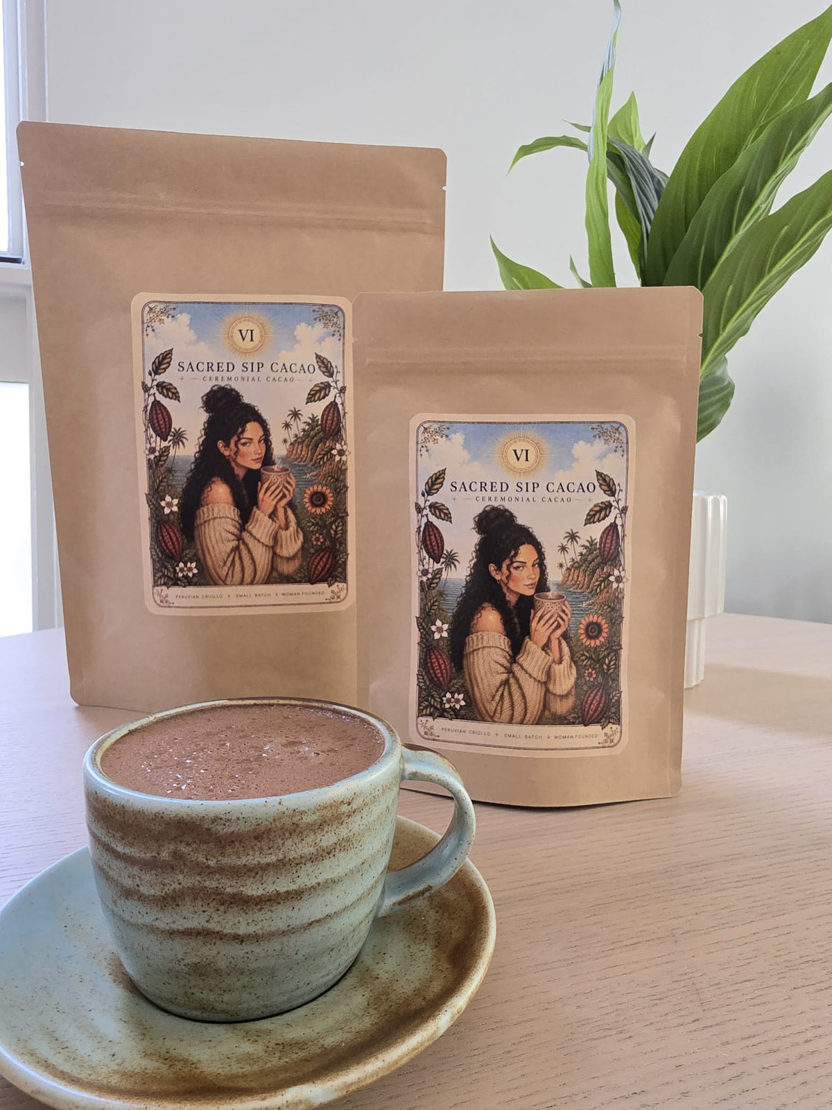 Two Sacred Sip Cacao pouches beside a mug of prepared ceremonial cacao